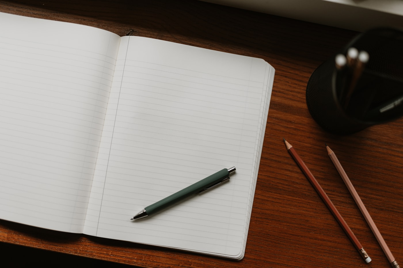 An open notebook and pen on a wooden desk