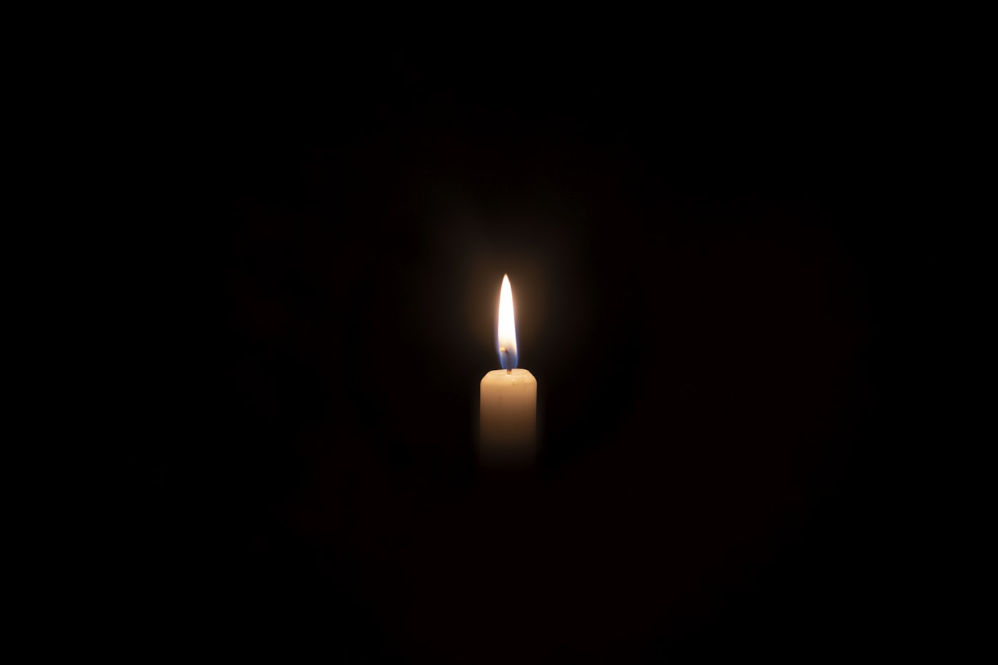 A single lit candle against a dark background